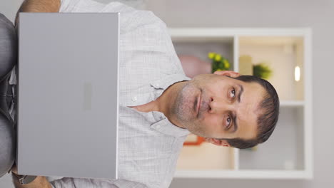 Vertical-video-of-Man-looking-at-laptop-is-unmotivated-and-bored.